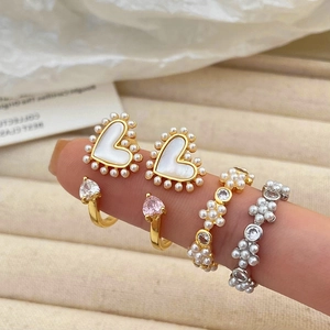 Detail van een gouden ring met hartvormige parels en roze zirkonia stenen op fluweel