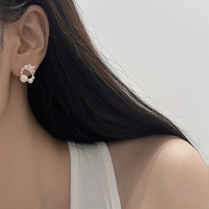Dettaglio di orecchini a cerchio con stelle marine e perle indossati da una modella
