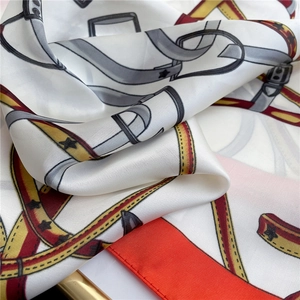 Macro shot of ivory silk scarf showing belt print details and soft satin texture