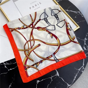 Detail of square silk scarf with horse harness patterns on a marble table