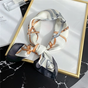 Close-up of silk square scarf featuring classic belt and buckle print in orange and grey