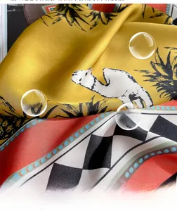 Close-up of silk-textured square scarf with yellow camel and pineapple patterns