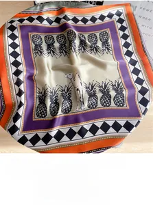 Detailed pattern of silk scarf with pineapple and camel print on wood background