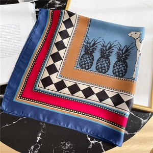 Detail of silk square scarf showing vibrant pineapple and camel prints on marble