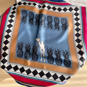 Detailed pattern of a silk scarf featuring a white camel, pineapple motifs, and chic checkers