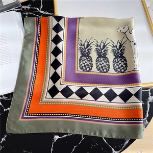 Detailed flat lay of silk-textured square scarf featuring artistic camel and pineapple prints