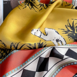 Detail of silk scarf with yellow camel prints and geometric patterns on black stone
