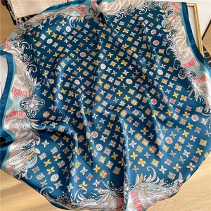 Peacock blue silk square scarf with crane print and clover pattern on wooden floor