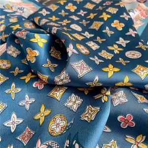 Detailed view of silk-like scarf with blue floral and geometric patterns