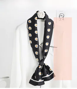 Detailed view of a narrow black silk scarf with white daisy floral print on a white shirt