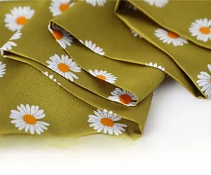 Macro detail of silk-like olive green scarf showing daisy print and neat inner stitching