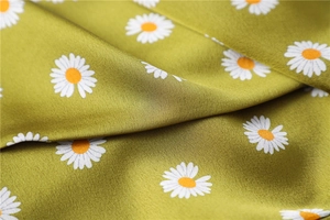 Close-up of olive green faux silk scarf fabric with daisy print and smooth texture