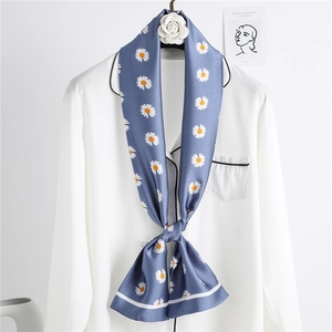 Close-up of a blue silk scarf with white daisy floral pattern tied on a white shirt