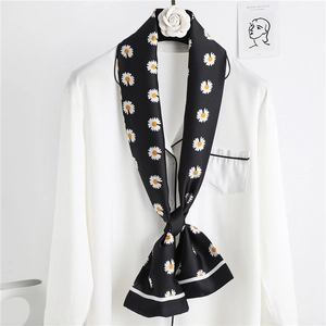 Detail of a black silk scarf with white daisy print tied around a white collar blouse