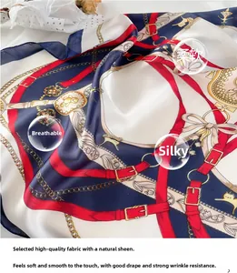 Detail of silk-feel scarf featuring golden chain and buckle patterns in navy and red