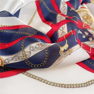 Detail of silk scarf with navy chain print and smooth satin texture on white background