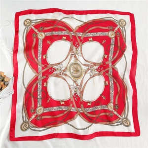 Detailed view of square silk scarf with vintage gold chains and red floral patterns