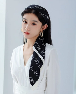 Close-up of a black silk scarf with white butterfly prints worn as a stylish headband