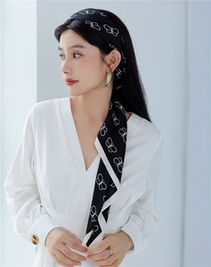 Detail of elegant black silk scarf with white butterfly print styled as a hair accessory