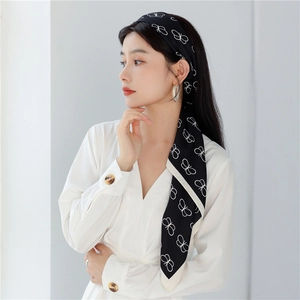 Detail of elegant black silk scarf with white butterfly print worn as a chic headband