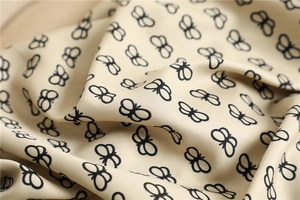 Detailed texture of silk shawl featuring black butterfly sketches on beige fabric