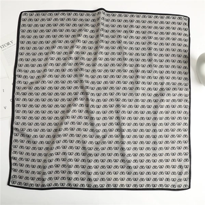Detailed view of large square silk scarf with black butterfly print on grey fabric