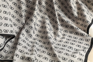 Close-up of lightweight light grey silk scarf with black butterfly print and hemmed edges