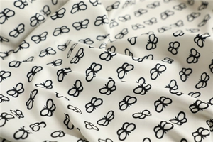 Detail of white twill fabric with black butterfly print showing fine woven texture