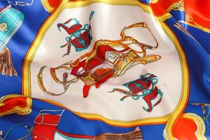 Close-up of silk-like satin scarf with classic equestrian carriage and bridle pattern