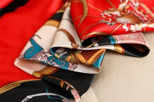Macro detail of silk satin square scarf with classic horse carriage print and red trim