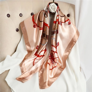 Elegant 90cm square silk scarf with champagne horse carriage pattern draped on a chair