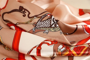 Close-up of silk scarf showing elegant horse carriage pattern and smooth satin texture