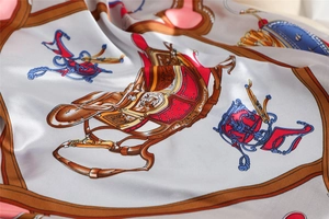 Detailed view of silk square scarf featuring classic horse carriage patterns and royal crests