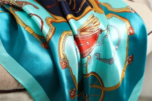 Detail of teal satin scarf showing glossy fabric folds and vintage carriage pattern