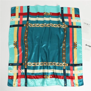 Détail d'un foulard carré bleu sarcelle avec motifs de chaînes et texture satinée