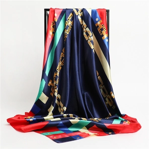 Détail d'un foulard en soie aux blocs de couleurs géométriques et imprimé chaîne dorée