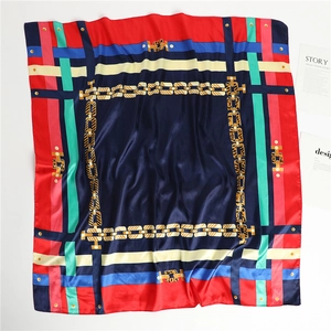 Détail du foulard carré en soie avec imprimé chaîne dorée et texture satinée
