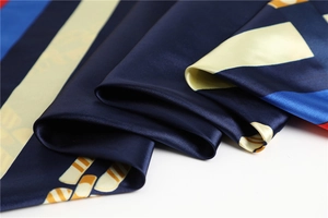 Vue détaillée d'un foulard en soie montrant des rayures géométriques et un éclat satiné
