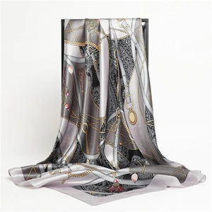 Détail d'un foulard en soie montrant des motifs de chaînes dorées et cordes sur satin