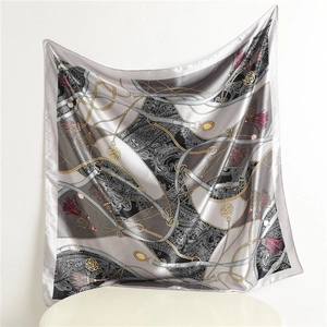 Vue détaillée d'un foulard en soie avec chaînes dorées et motifs paisley au drapé fluide