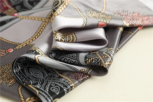 Détail d'un foulard en soie avec motifs de chaînes baroques et texture satinée