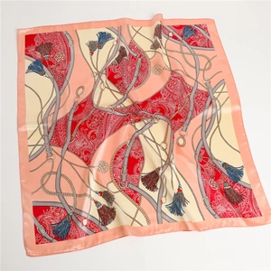 Détail d'un foulard en soie avec motifs paisley, lanières en cuir et chaînes en métal