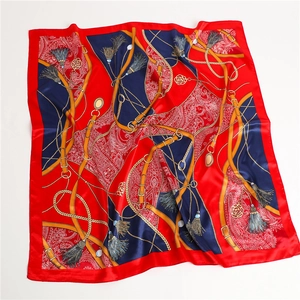 Détail du foulard carré rouge en soie avec imprimé ceintures et chaînes dorées rétro