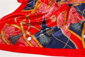 Détails de foulard en satin soyeux avec chaînes dorées et motifs paisley rouges