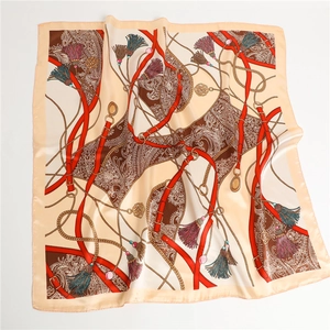 Détail d'un foulard carré en soie avec motifs paisley, chaînes dorées et ceinture rouge