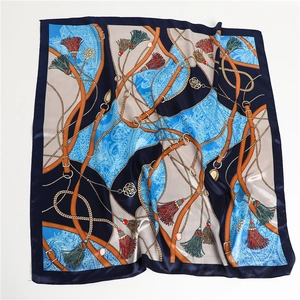 Détail de l'imprimé chaîne et ceinture sur foulard en satin bleu avec plis soyeux