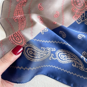 Detail eines grauen und marineblauen Paisley-Seidentuchs mit Satin-Textur und Rollsaum