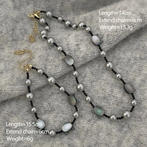 Macro view of grey pearl necklace and bracelet with cat shell charms and gold metal clasps