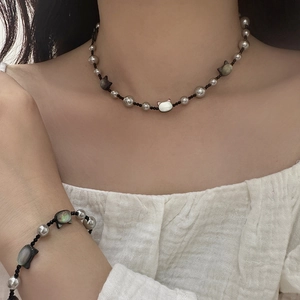 On-model view of a black cat pearl necklace and matching bracelet set
