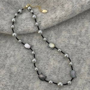 Detail of grey pearl necklace with cat shell pendants and gold lobster clasp